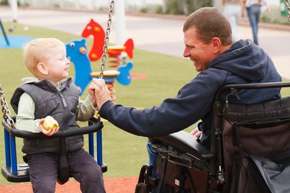 Disabled Father play with his little son on the playground.
Vater im Rollstuhl, gibt seinem kleinen Kind auf Schaukel Schwung