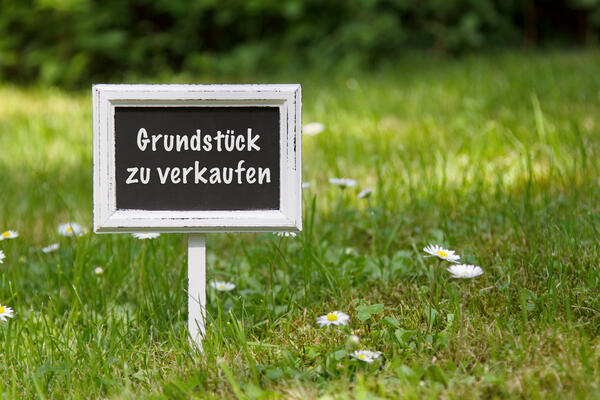 Foto von Schiefertafel-Schild "Grundstück zu verkaufen" auf Wiese