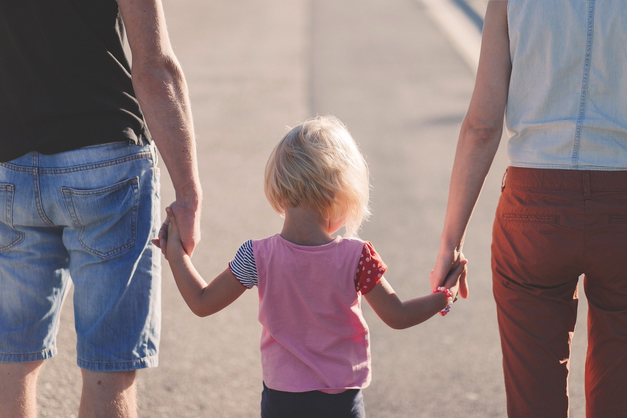 Familie mit Pflegekind beim Spaziergang (von hinten)