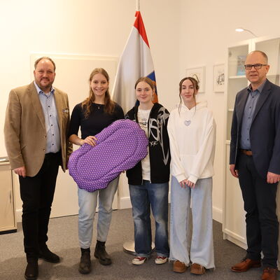 Die Gr&uuml;nderinnen mit Landrat Timo Gaarz (links) und Schulleiter Christoph Salewski (rechts) und dem "SleepyComfy"