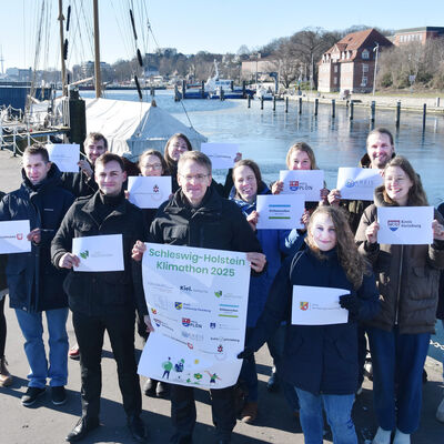 Ministerpr&auml;sident Daniel G&uuml;nther (Bildmitte) gibt zusammen mit den Klimaschutzmanagerinnen und -manager der Landkreise und St&auml;dte den Startschuss f&uuml;r den Schleswig-Holstein-Klimathon 2025