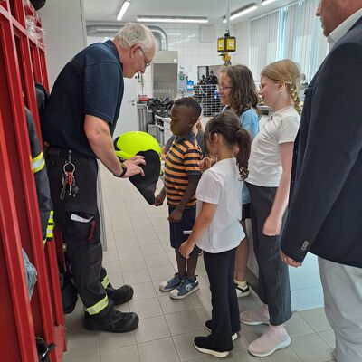 Bild vergrößern: Andy Geldmacher (FTZ) zeigt den Kindern die Feuerwehrausrstung