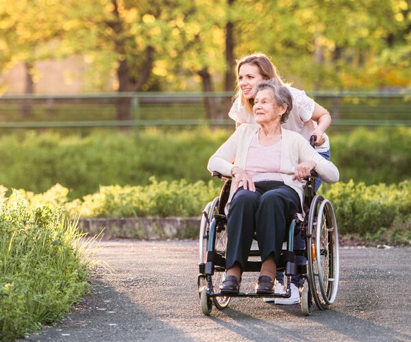 Bild vergr&ouml;&szlig;ern: Elderly grandmother in wheelchair with granddaughter in spring nature.
